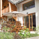 Table avec bancs et parasol pour les repas sur la terrasse.