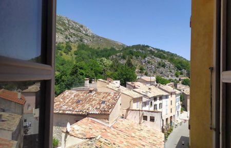 Vue de la fenêtre de la cuisine sur la place de la Combe (façade Est) Gîte n°1043 Coursegoules - Alpes-Maritimes - Vue de la fenêtre de la cuisine sur la place de la Combe (façade Est)
